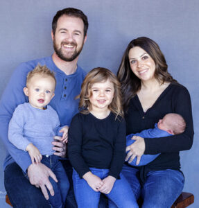 Here's an alt tag for the image: Happy family portrait with three children.